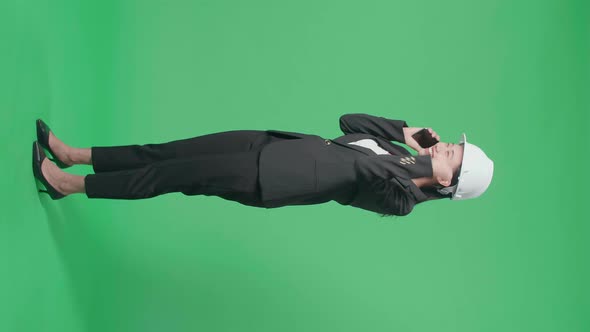 Full Body Of Female Engineer Celebrating While Talking On Smartphone In The Green Screen Studio