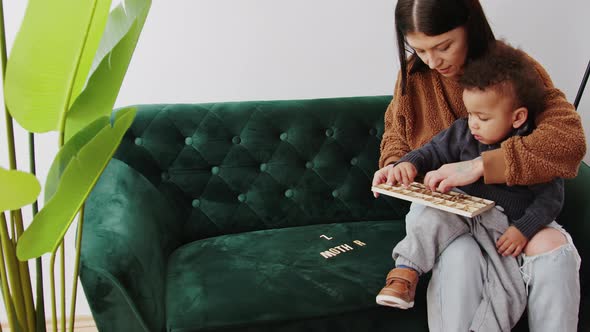 Mom and Little Boy Playing with the Wooden Letter on the Sofa Medium Full Shot Living Room