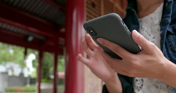 Close up of woman use of mobile phone in Chinese garden