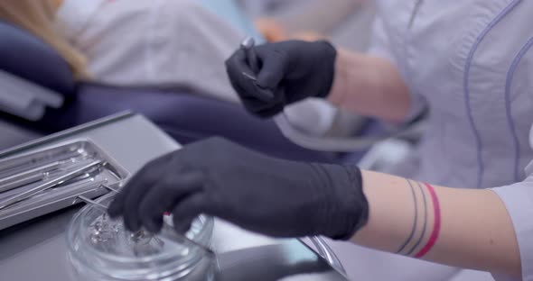 Dentist Takes a Drill with Tweezers and Inserts It Into the Drill