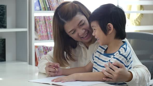 Asian Mother Helping Her Son Doing Homework On White Table Slow Motion