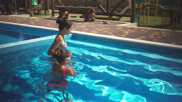 Elder Sister in Leopard Swimsuit Pulls Little Sister Out of the Pool with Blue Water