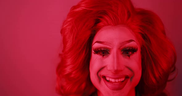 Drag queen smiling on camera with red light inside studio - Lgbtq concept