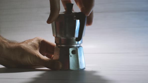 Man's hands assemble a geyser coffeemaker ready to make coffee
