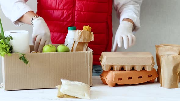 Volunteer in Protective Medical Mask and Gloves Putting Food Donation Box.