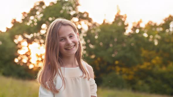 Portrait of Cute Girl in White Summer Dress Smiling and Looking at Camera While