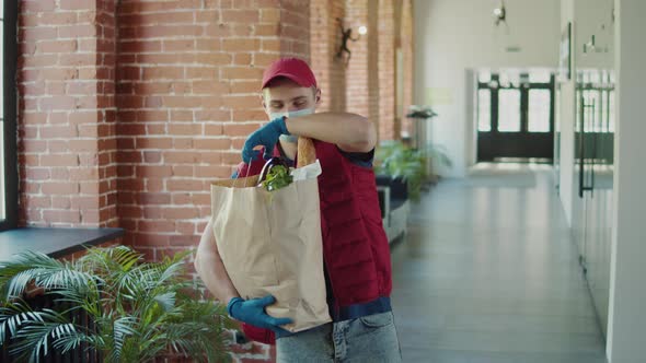 Postman or Delivery Man in Mask During Coronavirus Carry Small Box Food Deliver to Young Woman