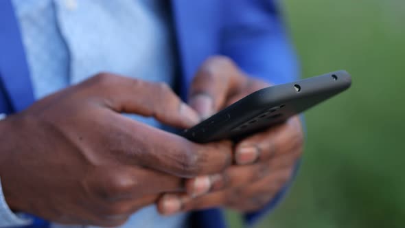 Black Man in Blue Blazer Enters Information Into Phone