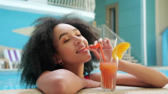 African American Woman in Red Swimsuit Drinking Non-alcoholic Orange Cocktail From Straw, Relaxation