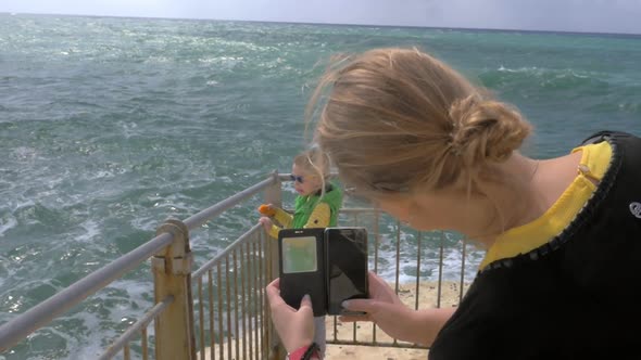 Mom taking cell photo of child looking at sea Rosh Hanikra