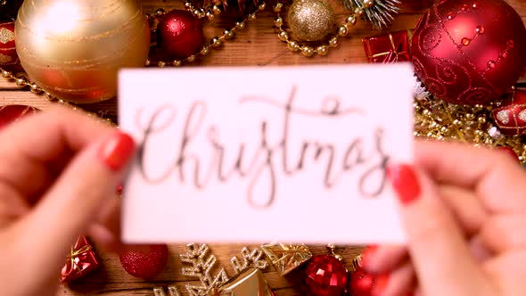 Hands put a card with text CHRISTMAS on a table