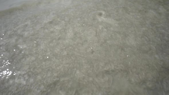 woden stick pass in the frame andes the water in a grey muddy puddle, top shot