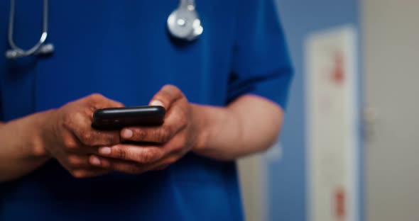 A Doctor Uses a Mobile Walking Along the Corridor of the Medical Center