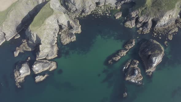 Bird's eye view of sea cliffs, rocks and clear ocean water of Ireland