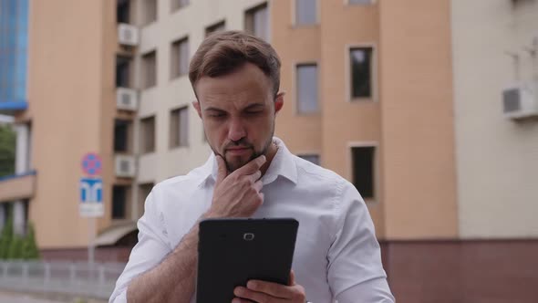 Handsome Man Uses His Tablet and Scratches Beard