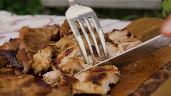 Hand Holding Knife Cutting Grilled Meat Steak on A Wooden Board