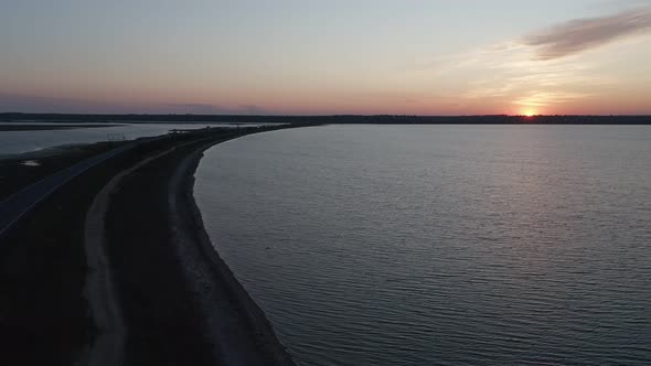 An Aerial View of a Car Is Driving at Sunset Near the Lake