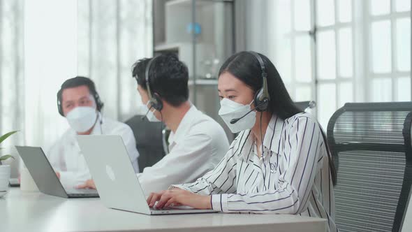 Woman Of Three Call Centre Agents Wearing Mask, Speaking To Customers While Colleagues Talking Are