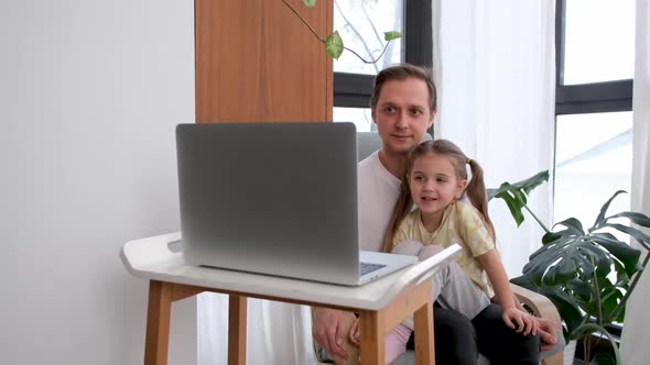 Father and Daughter Use Laptop at Home