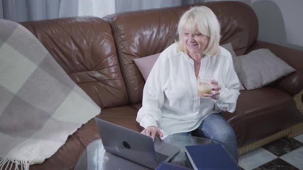 Top View of Attractive Senior Caucasian Woman Watching Pictures or Photos on Laptop Screen and