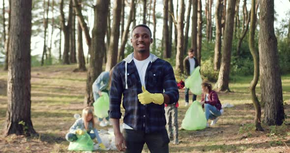 Volunteer Looking at Camera on the Background of Group of which Cleaning the Park