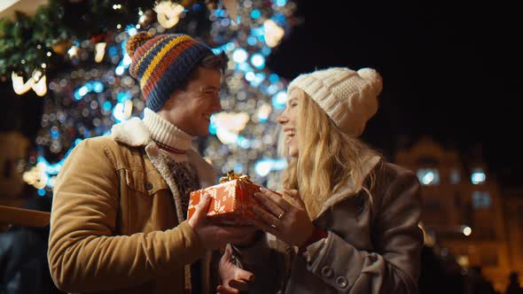 Young Man Gives a Girl a Gift for New Year and Christmas on the Streets of New York