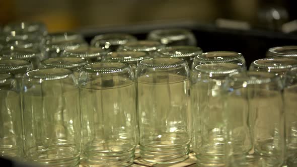 Jostling glass jars moving on production line. 