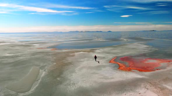 Aerial of a young girl walking on a desolate landscape by the great salt lake.