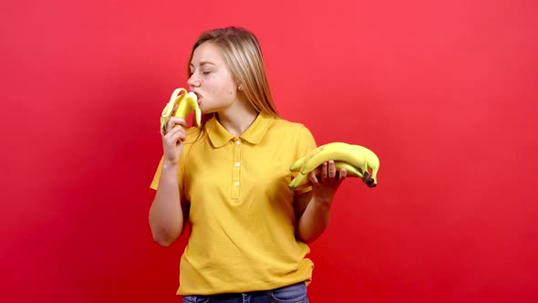 Cute and Slightly Fat Girl in a Yellow T-shirt Peels a Banana and Eats It