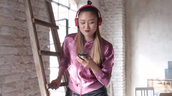 4k ultra hd young woman indoors listening music using smart phone