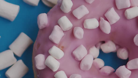 Pink Donut with White Marshmallows Rotates on a Blue