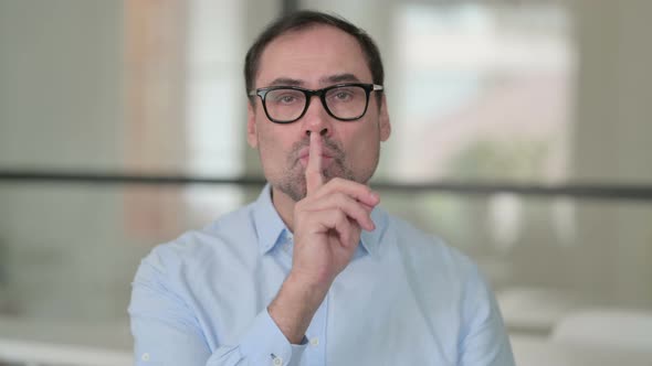 Middle Aged Man Showing Quiet Sign Finger on Lips