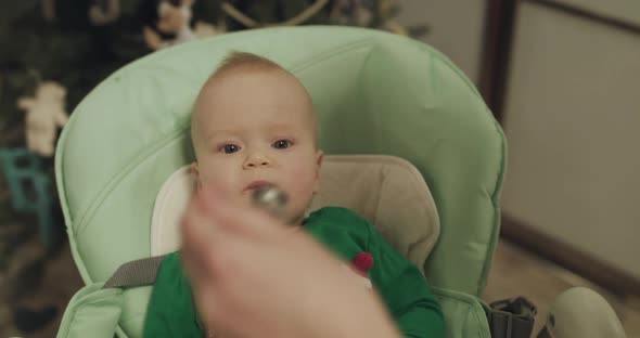 Cute Toddler in Kid Chair Eating From Spoon and Coughing