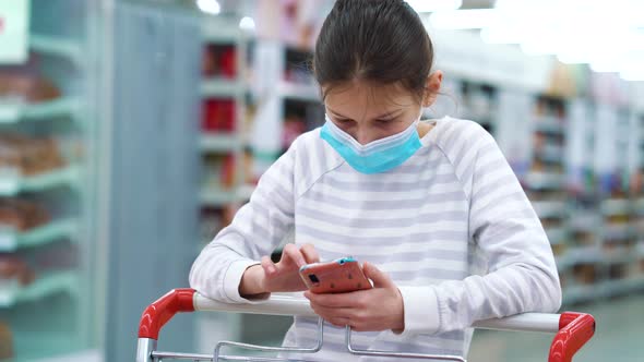 Girl playing game on smartphone in supermarket during pandemic