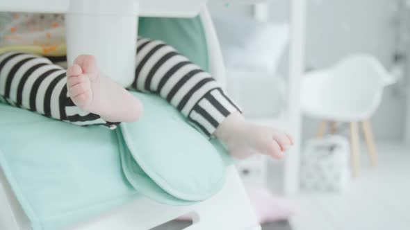 Legs of Baby Sitting on High Children's Chair alt