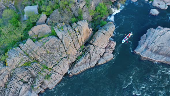 Aerial View of a Kayak Floating on a Turbulent River Between Stone Cliffs