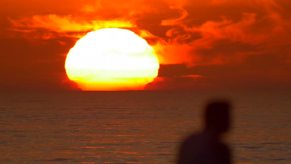 Silhouette of a man watching the sunset at the beach.