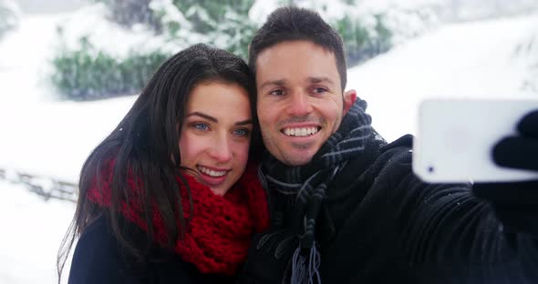 Couple taking selfie on mobile phone during winter