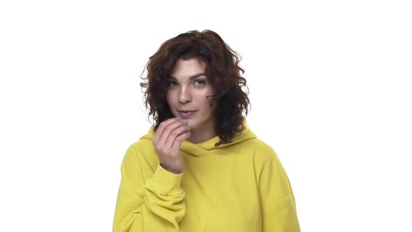 Shy and Coquettish Attractive Young Woman in Yellow Hipster Hoodie Blowing Wind Kiss and Glancing