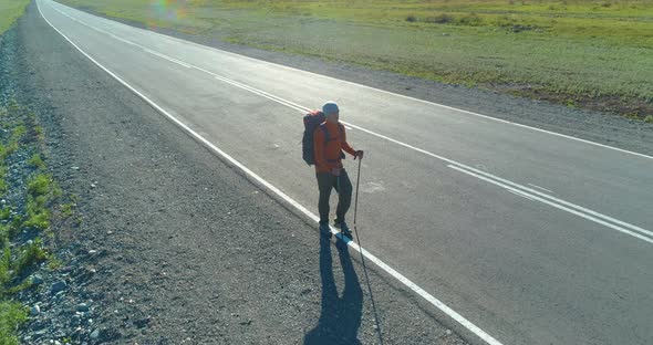 Flight Over Hitchhiker Tourist Walking on Asphalt Road, Huge Rural Valley at Summer Day, Backpack