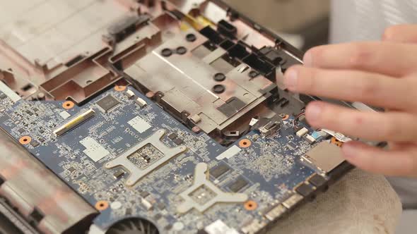 Closeup of technician hands repairing laptop computer cooling system.