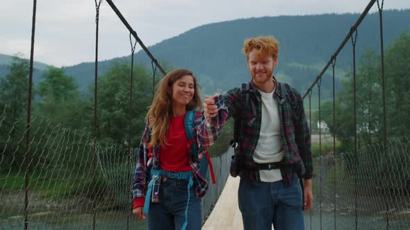 Hitchhikers Walk Mountains Together on River Bridge