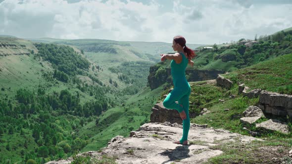 Athletic Girl Practices Yoga on the Edge Mountain