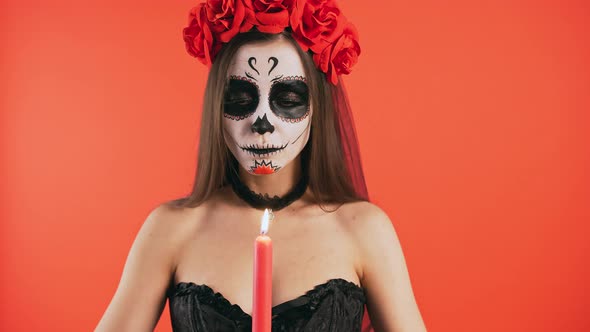 Day of Dead Lady with Skull Makeup Rasing Up Burning Candle Extinguishing It and Smiling Posing on