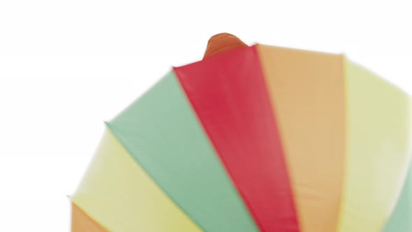 Happy Caucasian Middleaged Man Holding and Spinning Around Rainbow Colorful Umbrella to Protect Him