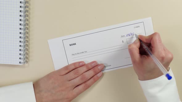 Hands of a Business Woman Close-up. Signing and Filling Out a Bank Check