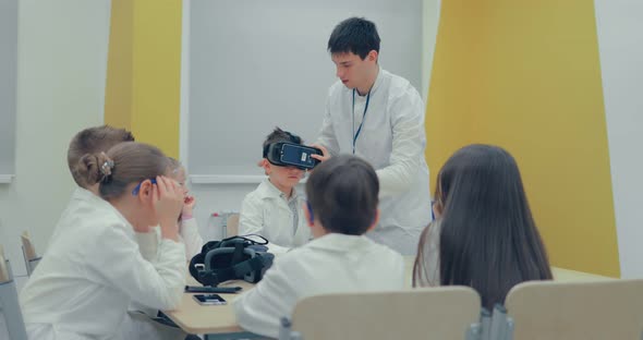 Little Boy in Virtual Reality Headset Standing in Classroom and Looking