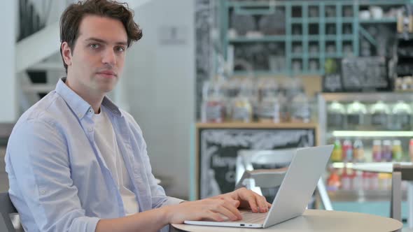 Thumbs Up By Creative Man with Laptop in Cafe