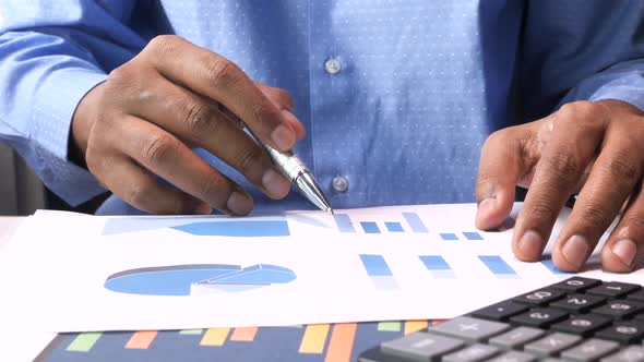 Man Hand with Pen Analyzing Bar Chart on Paper 