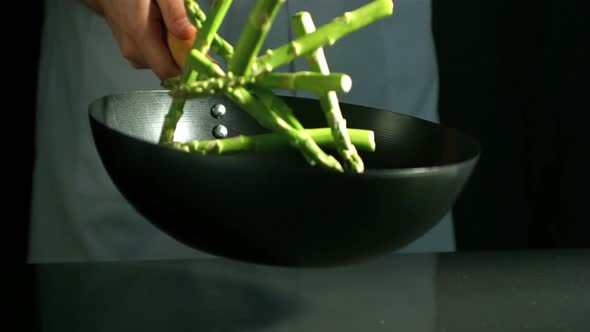 Chef tossing wok of asparagus